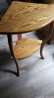 Side view of the oak corner table showing the curved legs and lower triangular shelf.