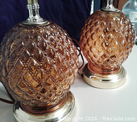 Close-up of the orange glass hobnail pineapple shaped lamp bodies with visible textured glass and metallic bases, showing wear and a small dimple on one lamp.