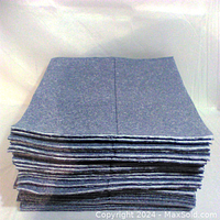 Stack of 25 blue-gray absorbent mats, folded and stacked.