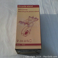Photo of the Arespark bicycle phone holder box showing product illustration and description text 'Bicycle stand, New arrival, New bicycle phone stand'. Box indicates product colors black and silver with pictograms for bicycle, motorcycle, and phone compatibility.