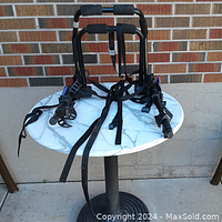 Front view of the assembled bicycle carrier showing padded support bars and locking straps on a white round table against brick wall.