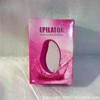 Photo of the front of the Epilator box showing brand name and pink splash design.