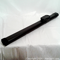 Side angle view showing the cylindrical black hard case with small side pouch and closed end.