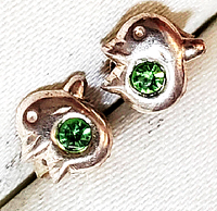 Close-up photo of the pair of sterling silver dolphin earrings with green garnet stones set in each dolphin shape.
