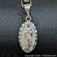 Front view of oval sterling silver pendant with Virgin Mary figure and radiant pattern.