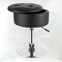 Vanity stool showing round tufted black PU leather seat partially lifted to reveal storage compartment, chrome pedestal base, adjustable height lever visible.