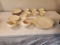 Full set showing six teacups, six small plates, two creamers, sugar bowl, and serving platter, arranged on white cloth.