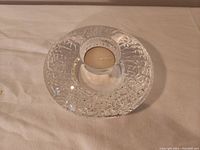 Clear crystal votive candle holder with textured circular design and central tealight candle holder on a flat surface.