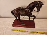 Leather horse statue on wooden base with measuring tape showing approximate size
