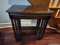 Set of three dark wooden nesting tables stacked together showing full structure and legs