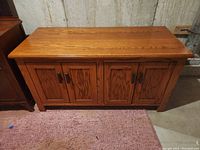 Front view of solid oak handmade sideboard showing four closed panel doors and natural wood grain finish.