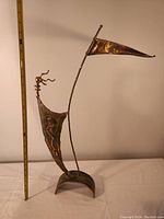 Full view of the abstract metal statue next to ruler for size reference showing it is about 2 feet tall.