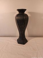 Photo shows the full black decorative vase with a textured stone-like finish and a slightly flared top opening.