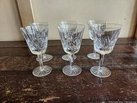 Six vintage Waterford crystal wine glasses arranged on a wooden surface, showing the diamond and wedge cut crystal pattern and starburst base.