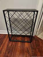 Full view of a black metal wine rack with a lattice design for storing wine bottles.