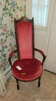 Full view of wood frame arm chair with red upholstery and turned legs, showing seat and arms.