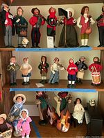 Seven figurines displayed on a wooden shelf, second row only.