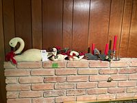 Full lot view showing three wooden swans, pewter and tin candle holders with red candles, and faux berries on brick ledge.