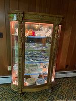 Full front view showing curved glass display, interior shelves, mirrored back, cabinet lights on