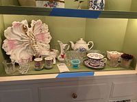 Shelf with lobster bowl, frog dish, teapot, cup and saucer, glass salt cellars and other vessels