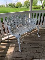 Front perspective of white wrought iron loveseat showing lattice seat and decorative back