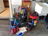 Photo showing the collection of car maintenance tools and items including jump cables, stool, wooden wheely cart, mops, and battery chargers
