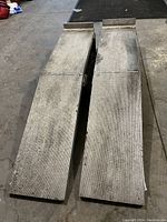 Pair of aluminum car ramps, top view showing textured surface and raised lip at the end.