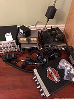 Overall view: two CB radios (one silver-face, one black), Astatic meter, Palomar Elite 300, Harley-Davidson box, microphones, antenna.