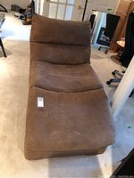 Front angled view of brown microfibre chaise lounge showing seat cushion and backrest with visible wear and some discoloration.