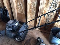 Side view of a Craftsman gas lawn mower with grass catcher, showing the handlebar and mower body.