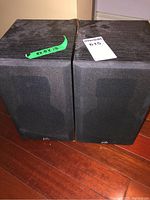 Front view of the pair of PSB speakers showing black cloth grilles and the woodgrain textured finish.