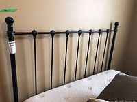 Front view of black metal headboard and attached rails against wall