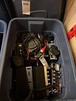 Plastic tub containing multiple CB radios, cables, and accessories
