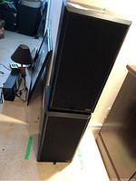 Photo showing two stacked black Szabo Audio Systems speakers.