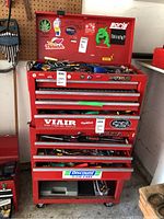 Front view of red multi-drawer tool chest with various decals and top compartment open
