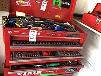 Wide angle view of tool cabinet open drawers and top showing assorted tools such as screwdrivers, sockets, Allen keys, and air hoses.