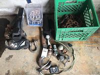 Full overview of tow bars, balls, chains in crate, hooks, and wiring items on floor.