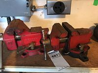 Two red SEARS 3.5 inch bench vises side by side showing overall condition and setup on wood surface.