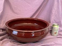 Front side of the large oxblood red Chinese bowl showing glaze color and finish, with soda can for scale comparison.