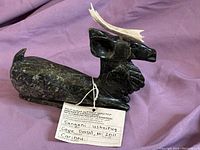 Front perspective of the dark stone Inuit carving showing the reindeer's body and antlers.