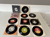 Top view of seven 7 inch vinyl records, some in original sleeves, showing various labels and conditions