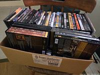 Box filled with assorted DVDs, including visible titles such as Cinderella Man and boxed sets of movies.