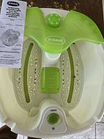 Top view of the Dr. Scholl's foot spa showing control knob, foot massage rollers, and instruction manual placed inside the basin.