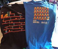 Two graphic T-shirts, left black Donkey Kong design, right blue Mario design, laid flat for overview.