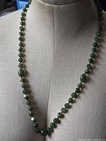 Full view of the green bead necklace displayed on a mannequin showing overall length and bead layout.