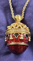Close-up of ornate egg pendant showing red enamel and detailed gold and black patterns