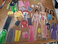 Full overview of the magnetic dress-up dolls with many magnetic clothes and accessories spread out on a table.