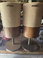 Pair of Electrohome mid century modern style speakers showing front view with beige patterned fabric covers and wooden bases.