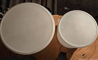 Top view of two circular Tupperware cake containers showing lids, one 13 inches in diameter and one 9 inches.