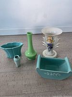 Lot of five Trenton Potteries ceramic pieces placed on floor near wall: white floral vase, tall green vase, two turquoise planters, small pale green mini vase